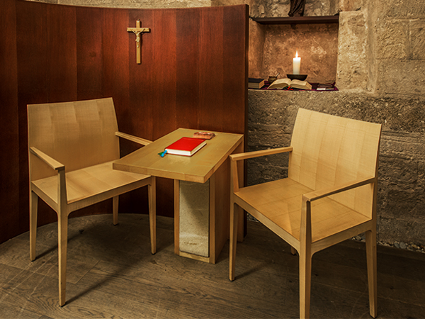 Beichtzimmer mit Stühlen, Tisch, heiliges Kreuz, Kerze und rotem Buch